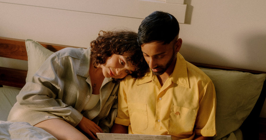 Woman resting her head on a mans shoulder while they sit in bed