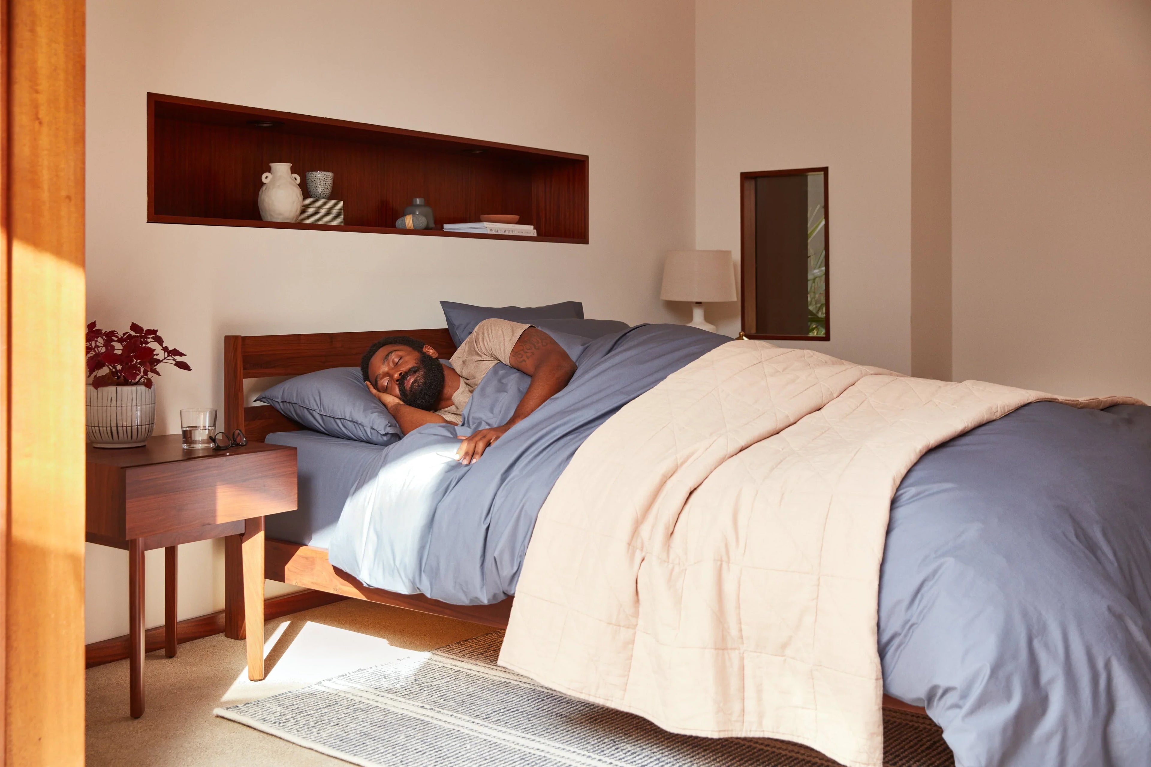 Woman laying on top of a Tuft and Needle Mint mattress with a charcoal colored blanket on top of her.