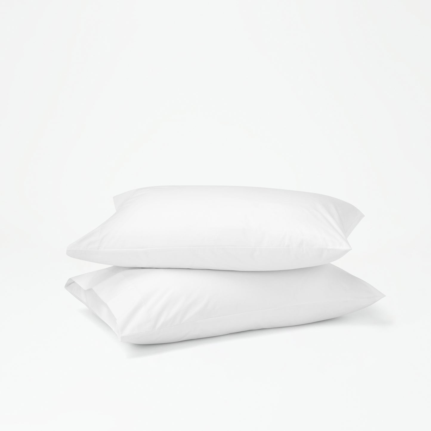 The Tuft and Needle Percale Pillowcase Set on two stacked pillows||color:cloud