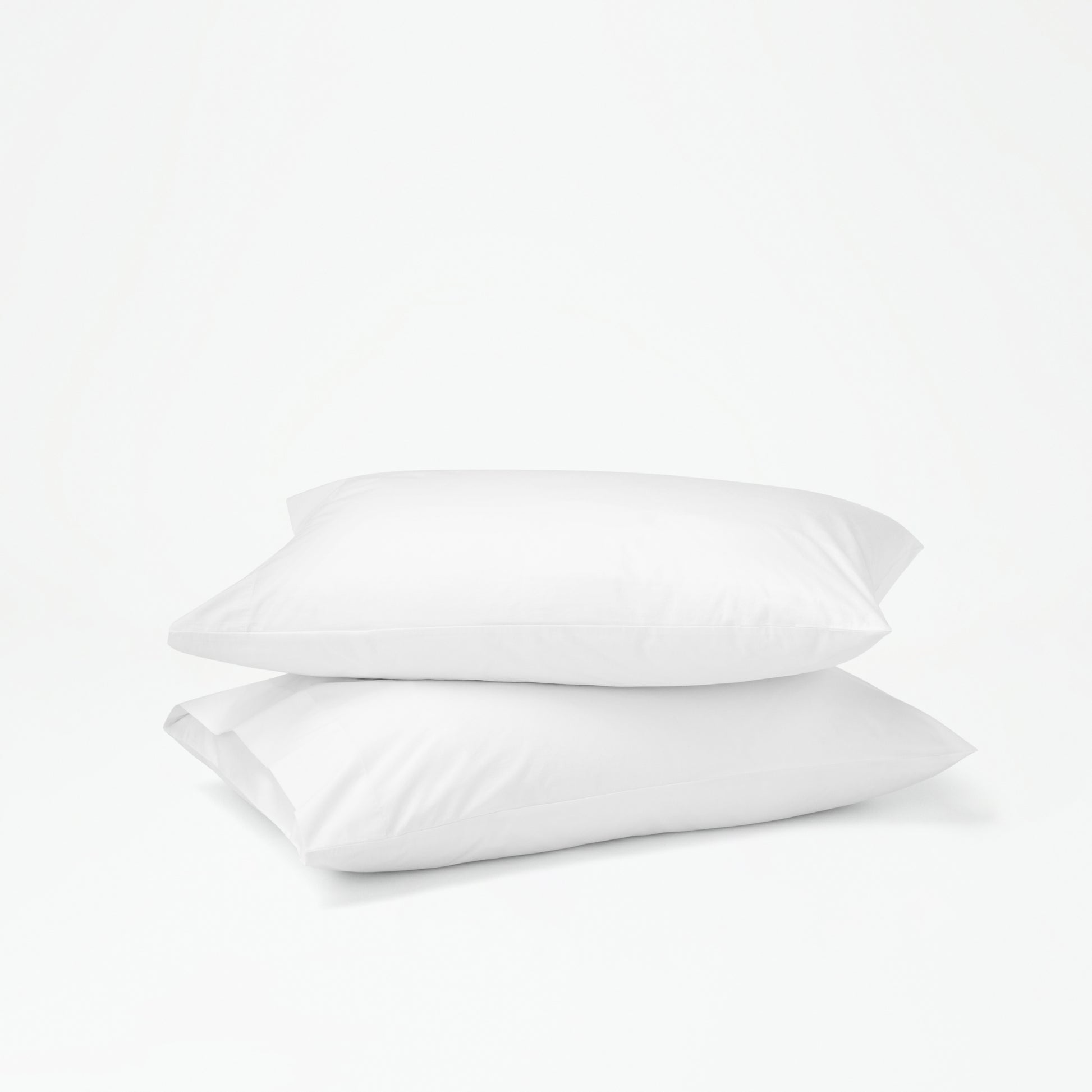 The Tuft and Needle Percale Pillowcase Set on two stacked pillows||color:cloud