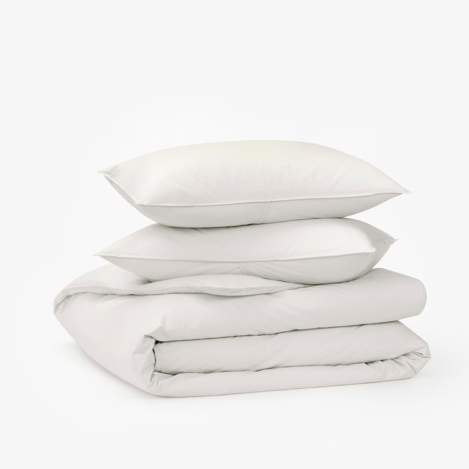 The Tuft and Needle Percale Duvet Cover Set folded and stacked on a white background||color:sand