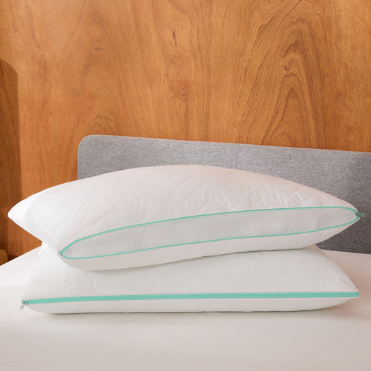 Two white Tuft & Needle Zip Comfort pillows with green edges on a bed against a wooden headboard.