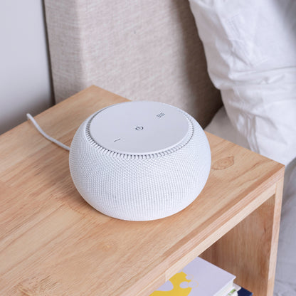  Tuft and Needle snooz pro white noise machine on a wooden side table with a neutral background