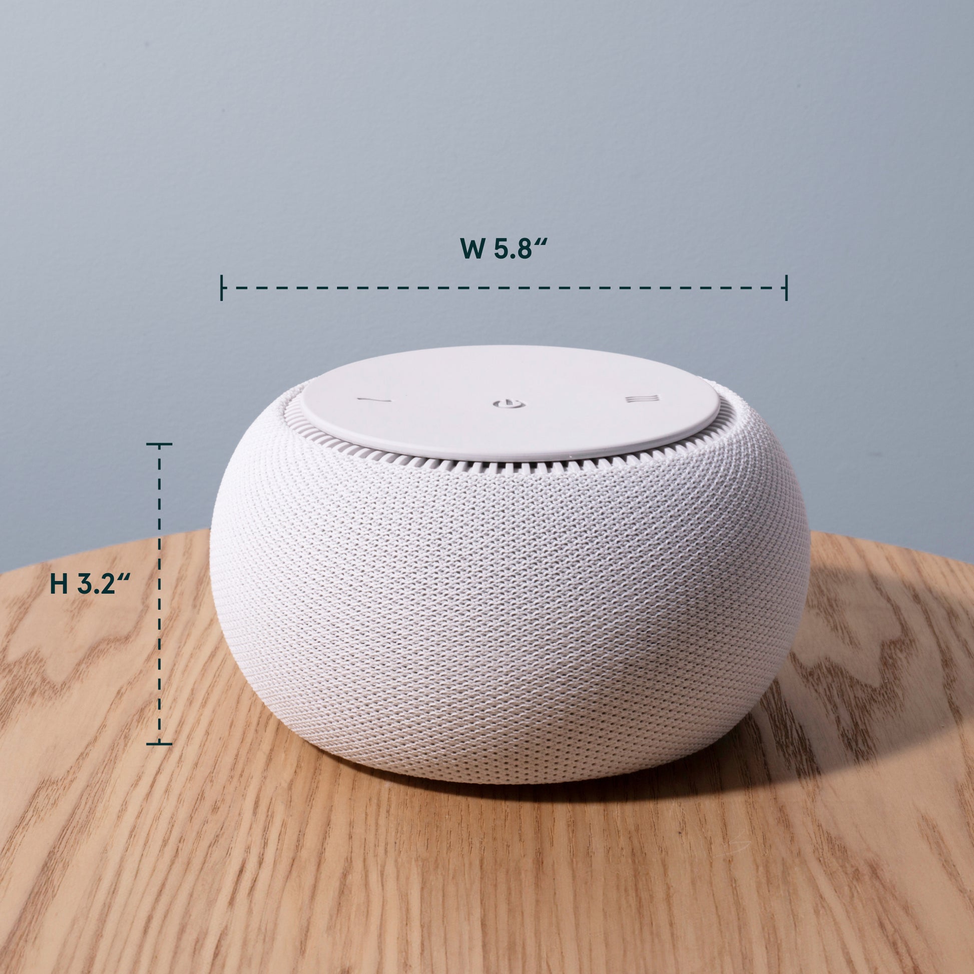 White smart speaker with dimensions labeled on a wooden surface and light blue background