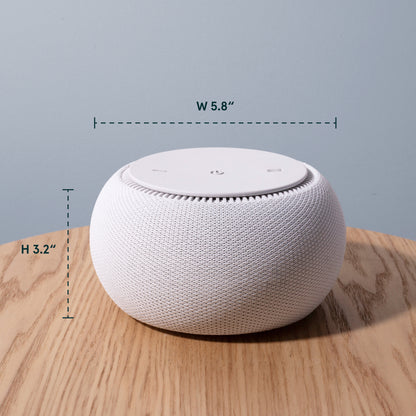 White smart speaker with dimensions labeled on a wooden surface and light blue background