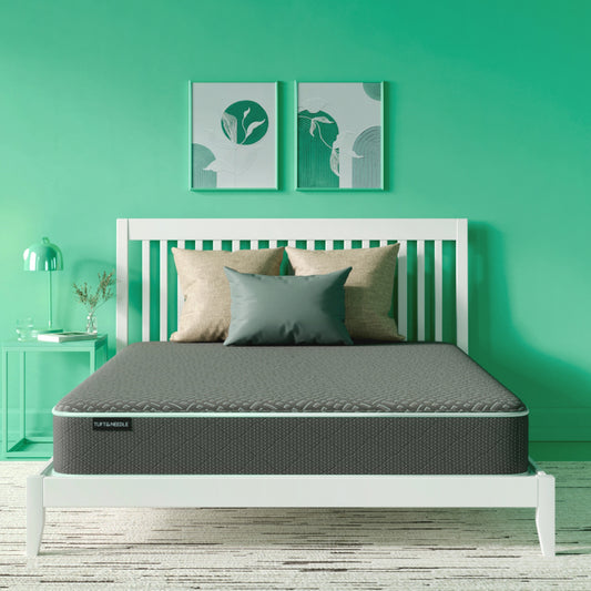 The Tuft and Needle Essential Hybrid Mattress in a green bedroom