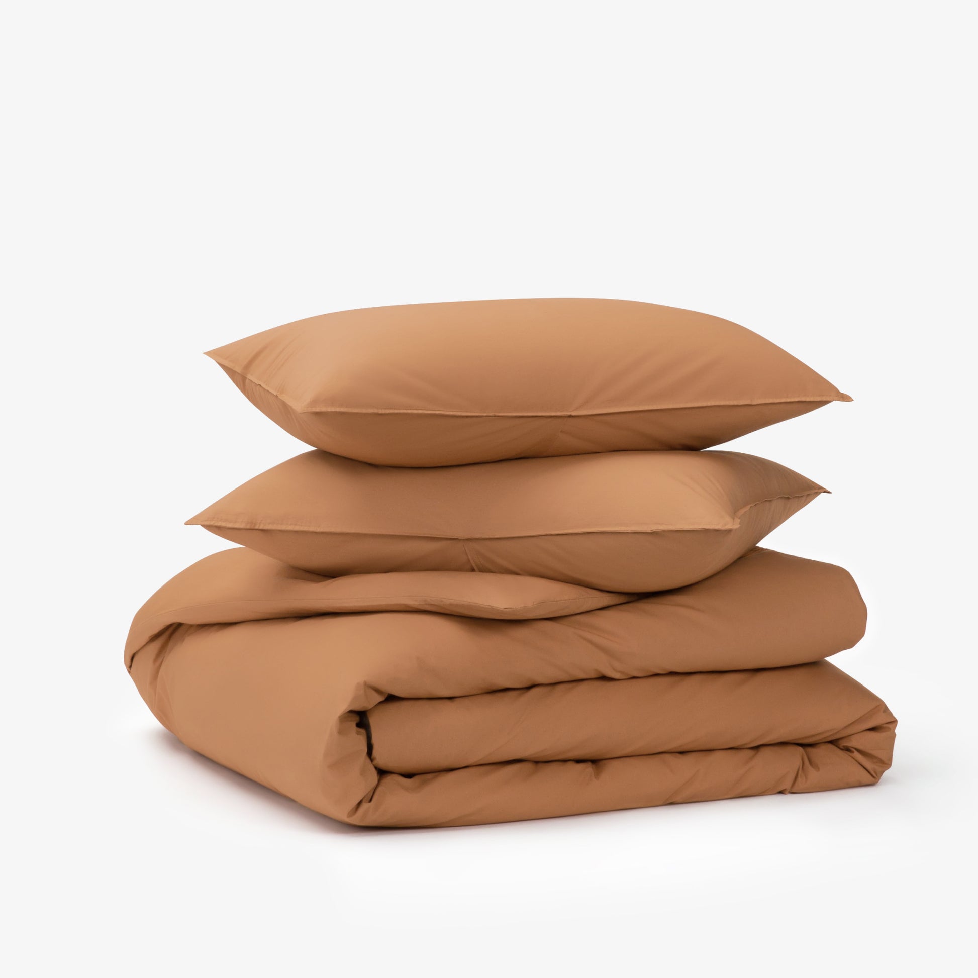 The Tuft and Needle Percale Duvet Cover Set folded and stacked on a white background||color:canyon