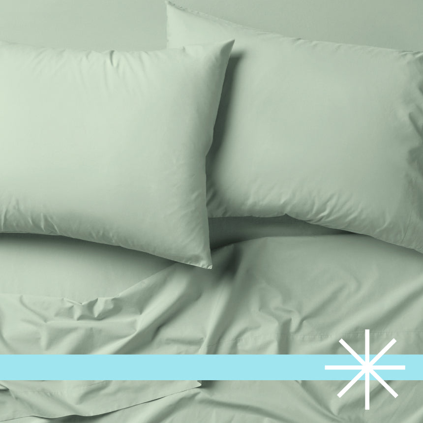 Tuft and Needle green bedding, two pillows encased in 2 green pillow cases on top of 2 sheets.