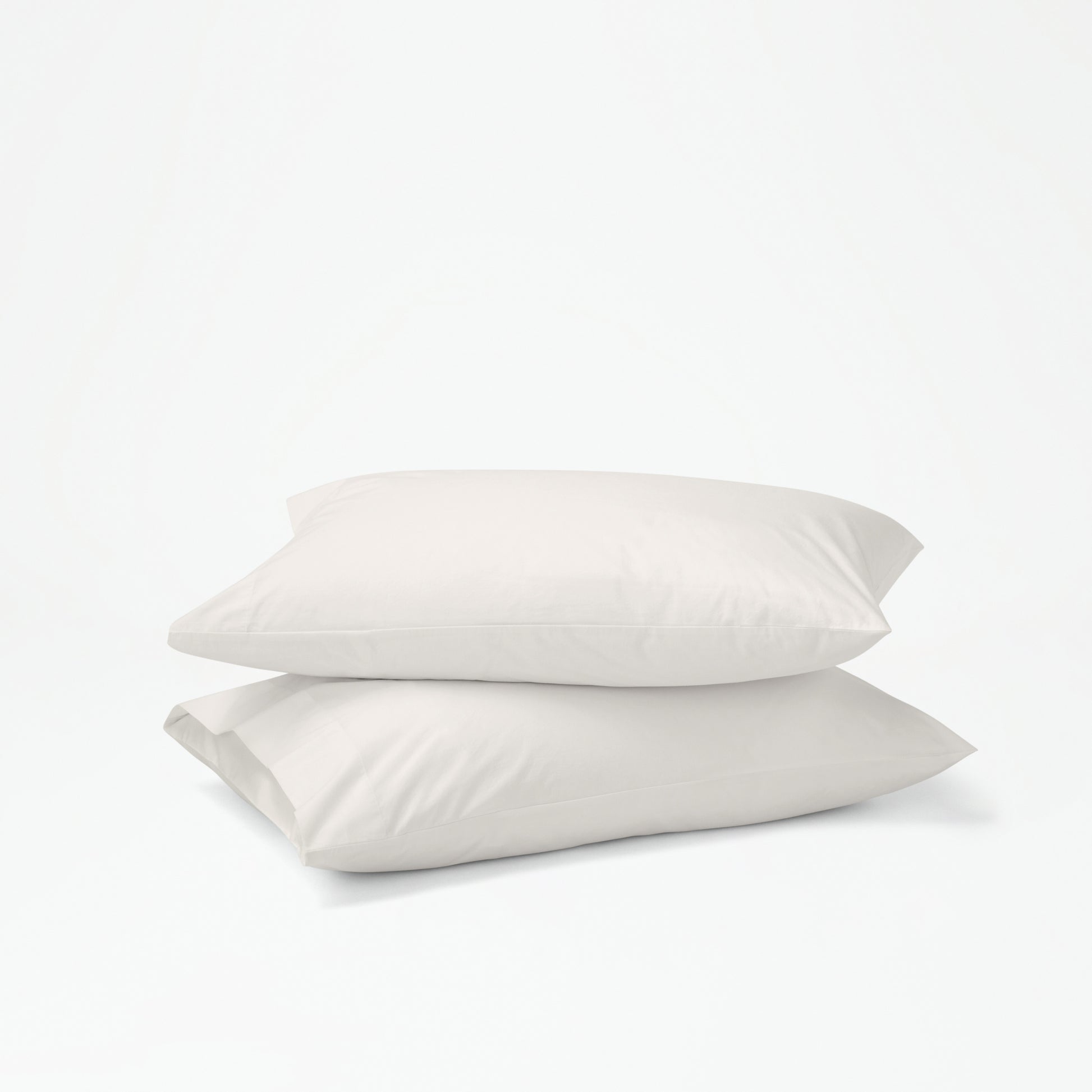 The Tuft and Needle Percale Pillowcase Set on two stacked pillows||color:sand