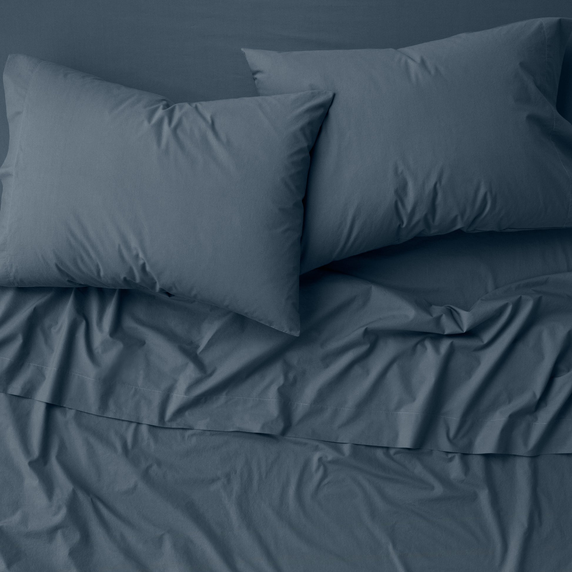 The Tuft and Needle Percale Pillowcase Set on a mattress ||color:slate