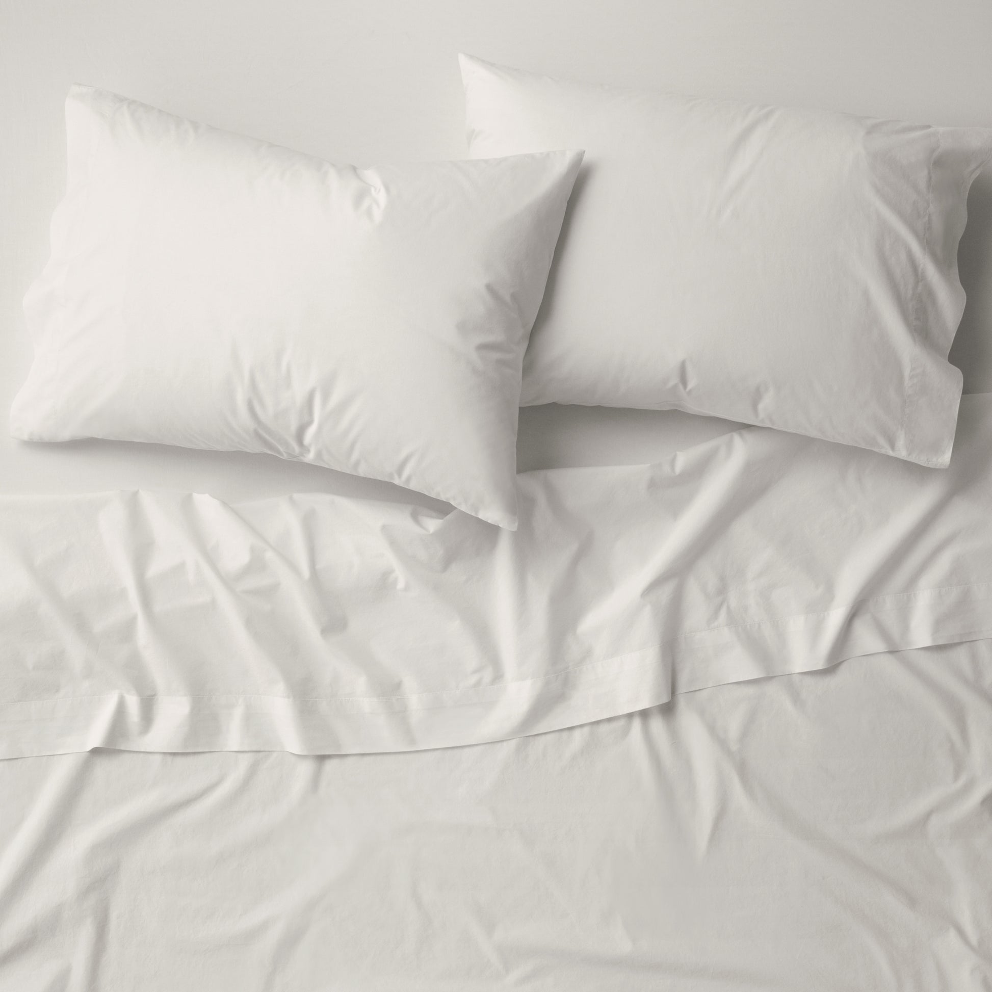 The Tuft and Needle Percale Pillowcase Set on a mattress||color:sand