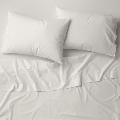The Tuft and Needle Percale Pillowcase Set on a mattress||color:sand