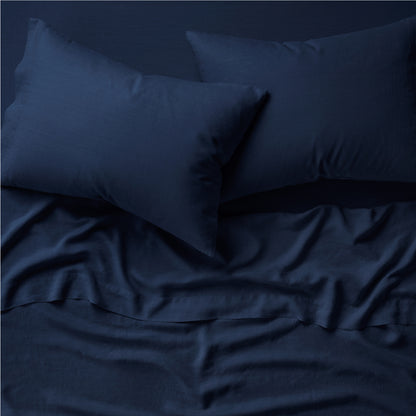 Two pillows on a bed dressed in the Tuft and Needle Hemp Pillowcase Set||color:midnight