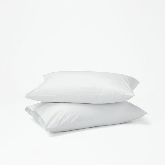 The Tuft and Needle Percale Pillowcase Set on two stacked pillows||color:glacier