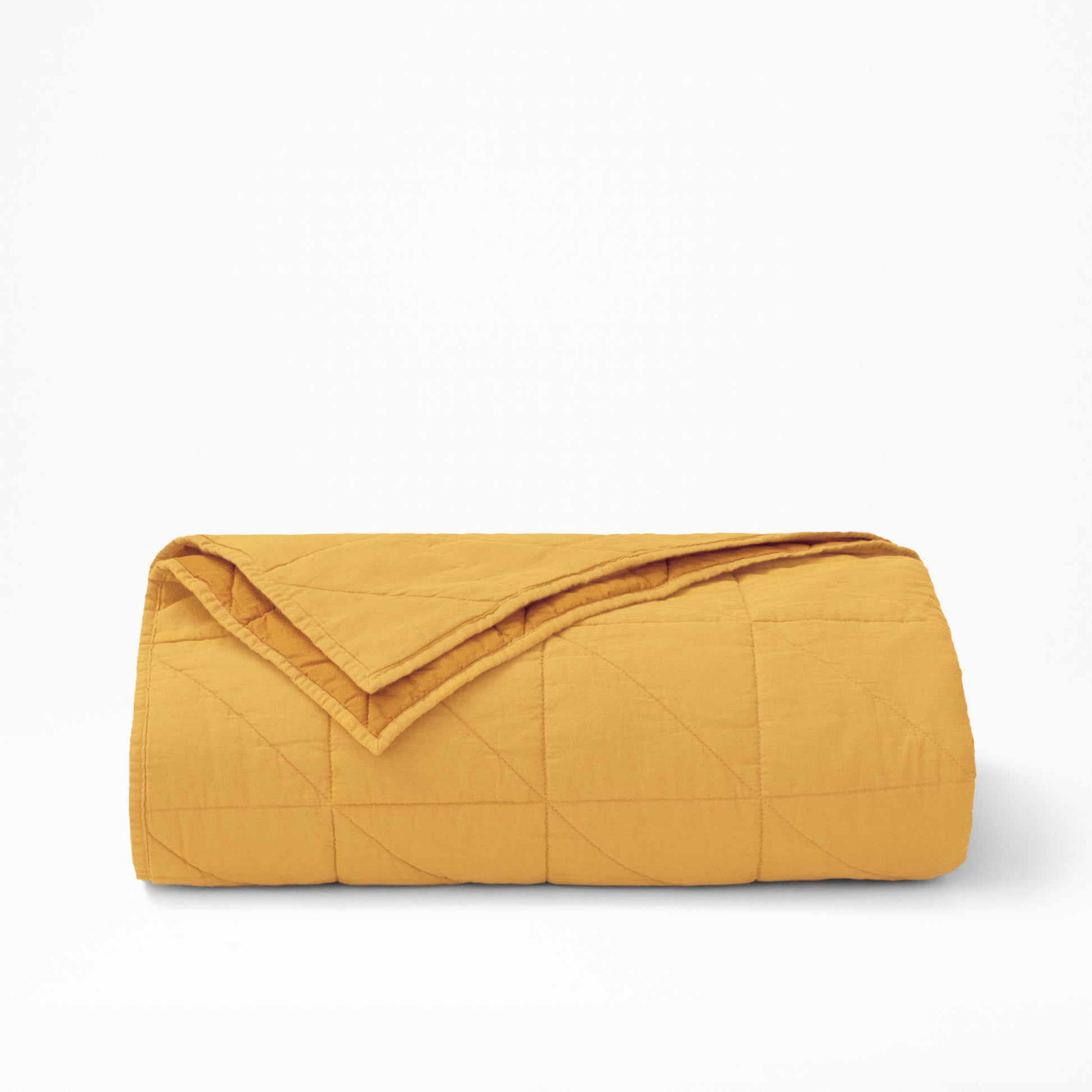 The Tuft and Needle Quilt folded. In color ochre