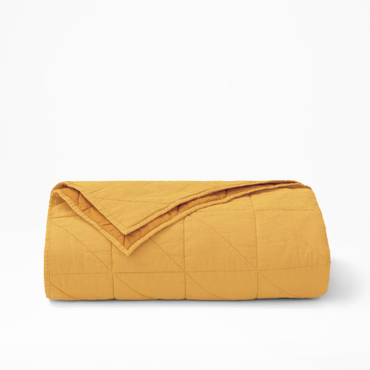 The Tuft and Needle Quilt folded. In color ochre