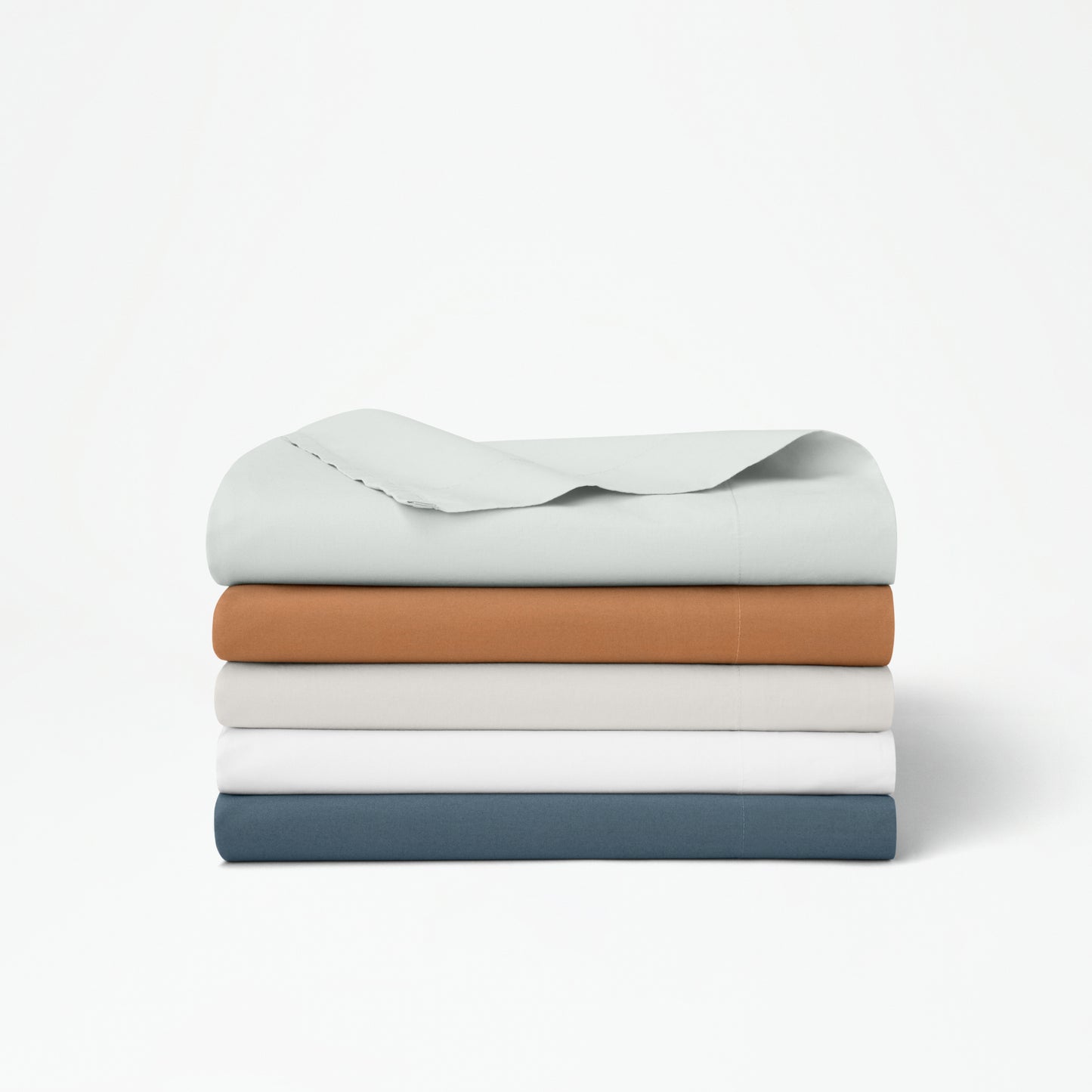 The Tuft and Needle Percale Duvet Cover Set folded and stacked on a white background||color:sand