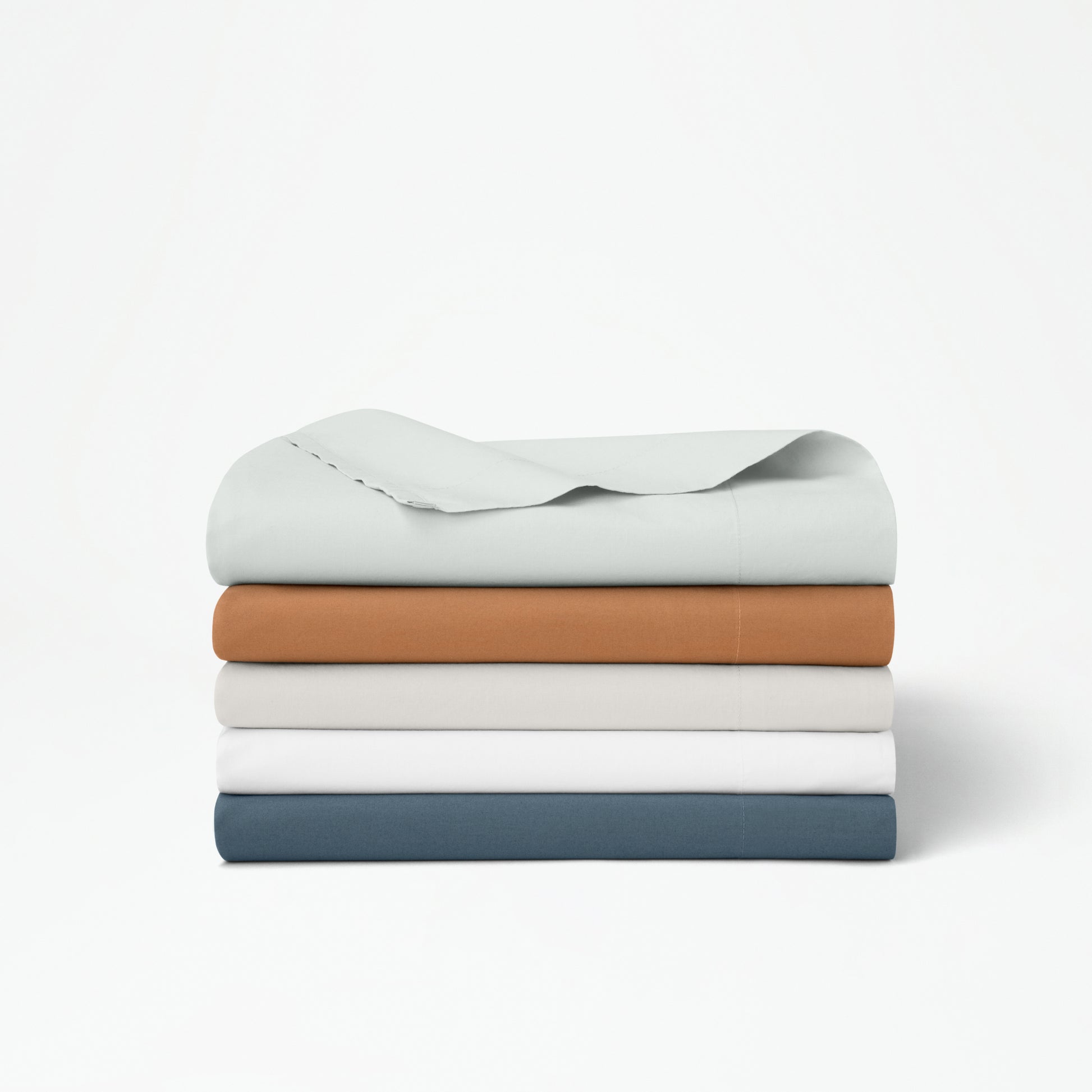 The Tuft and Needle Percale Duvet Cover Set folded and stacked on a white background||color:sand