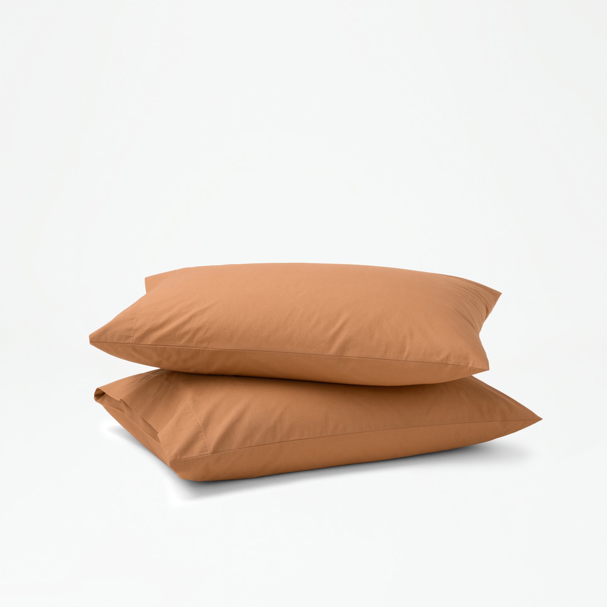 The Tuft and Needle Percale Pillowcase Set on two stacked pillows||color:canyon