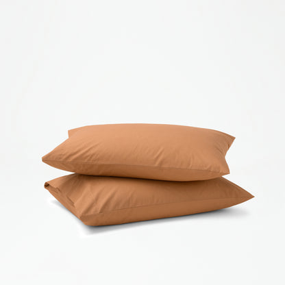 The Tuft and Needle Percale Pillowcase Set on two stacked pillows||color:canyon