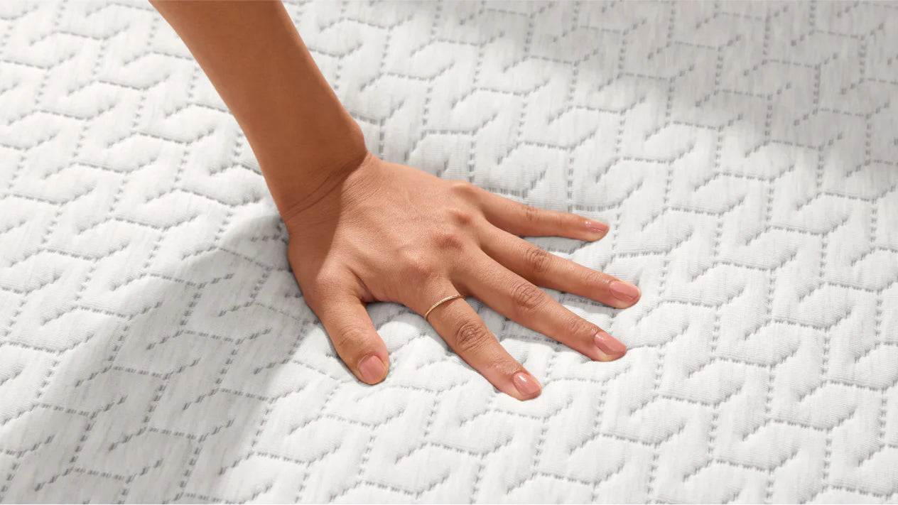 Woman's hand pressing down on the top of a foam mattress