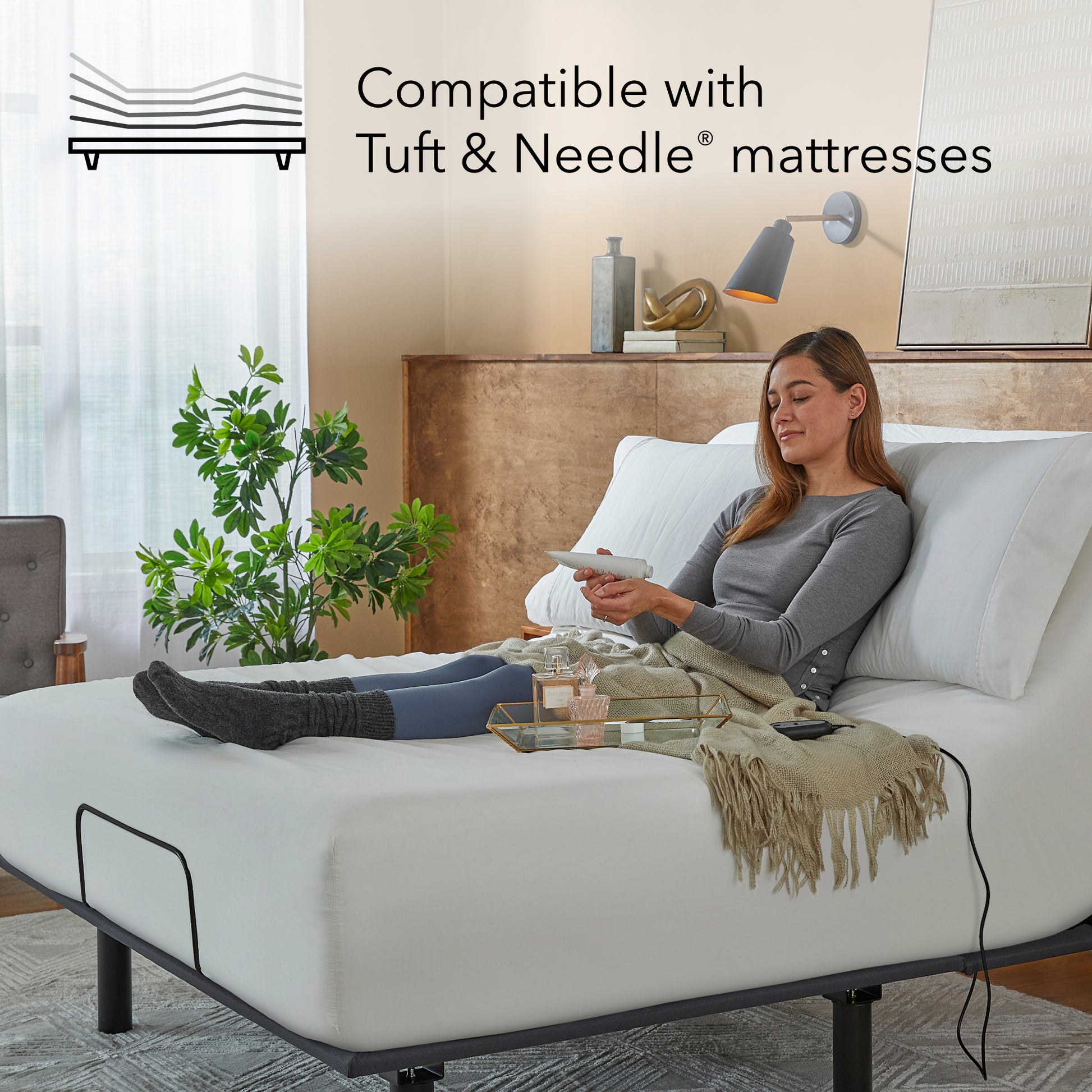 Woman sitting on a white mattress on a  Bronze baselogic adjustable base