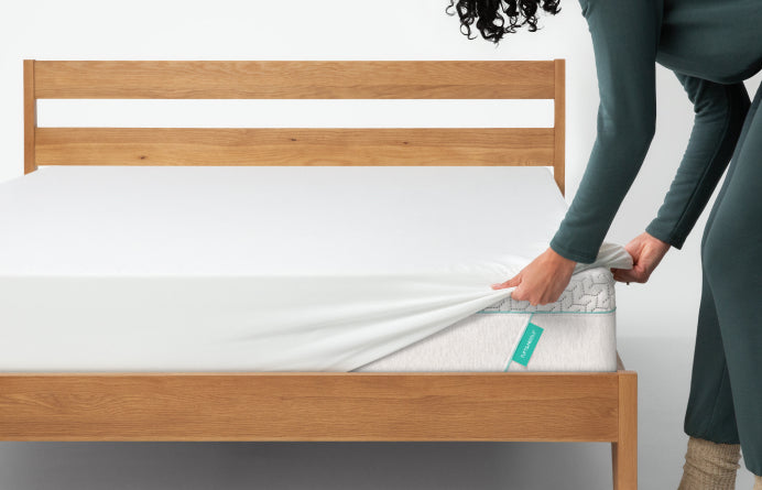 Man putting a mattress protector on his mattress 
