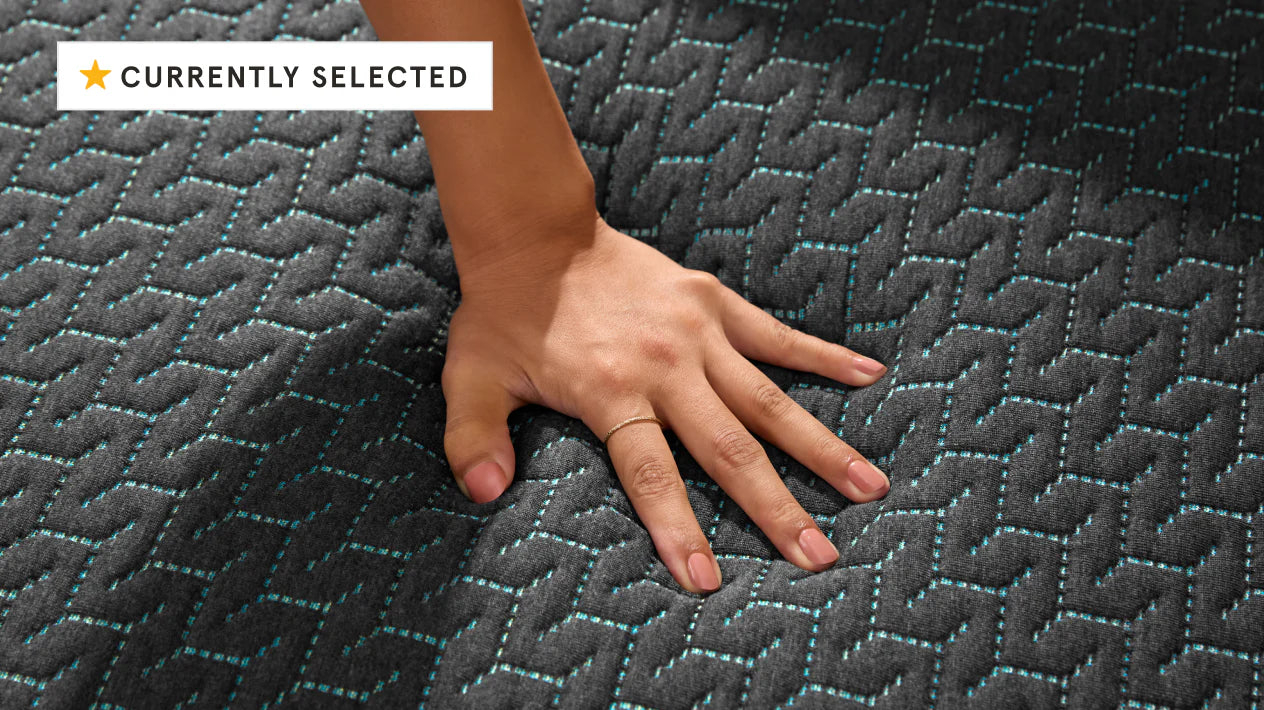 Womans hand pressing down on the top of a hybrid mattress