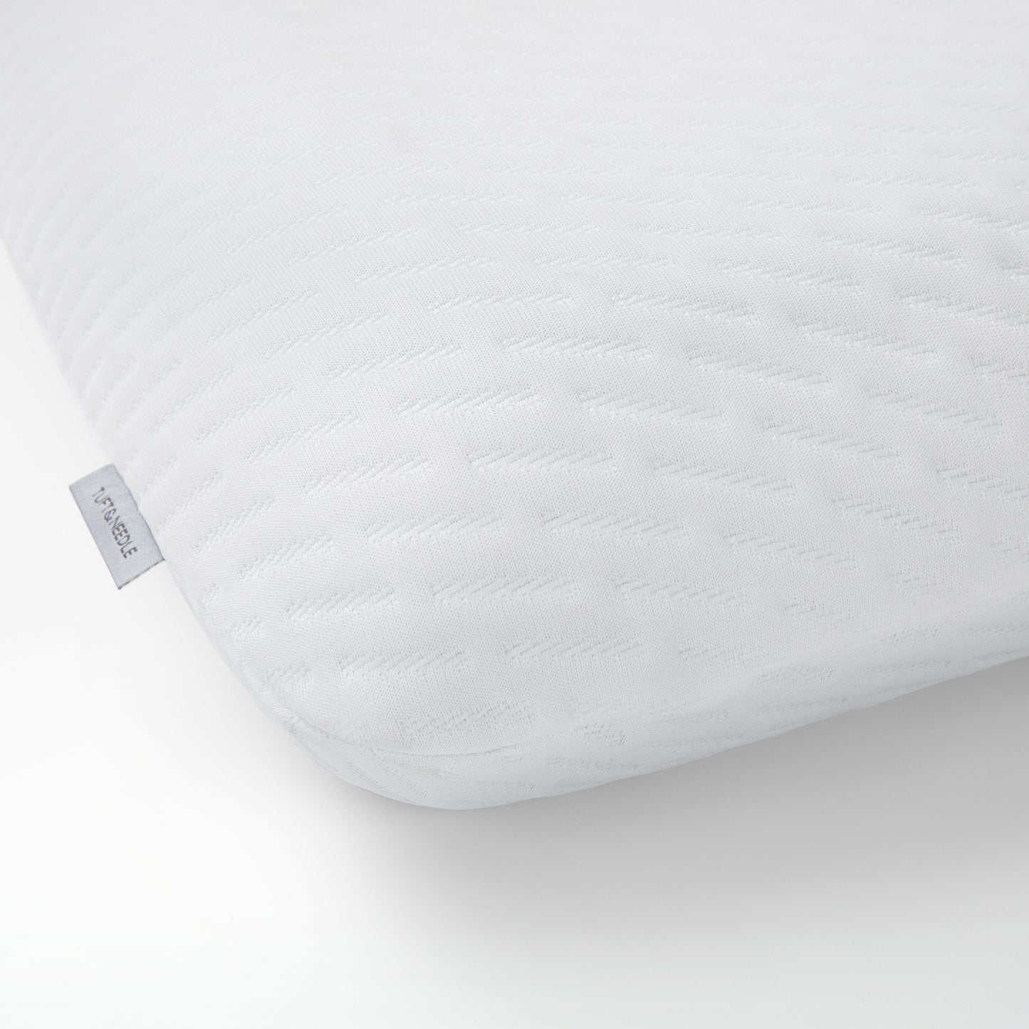 White Tuft and Needle foam pillow with a brand label on a white background