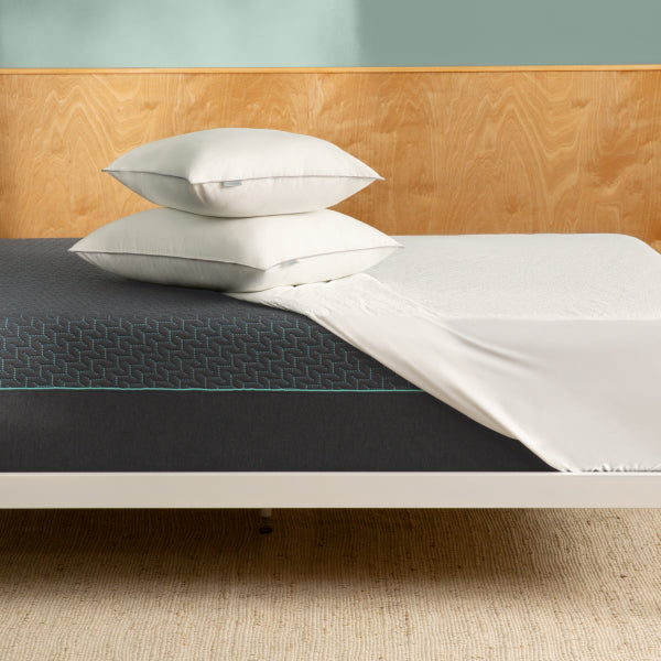 Tuft and Needle Mint mattress in a white bed frame with a white sheet and two pillows on top of it.