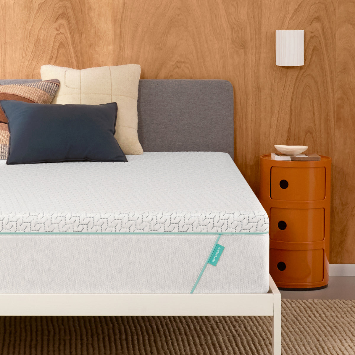 Tuft & Needle mattress in a white bed frame with 3 pillows on top of it.