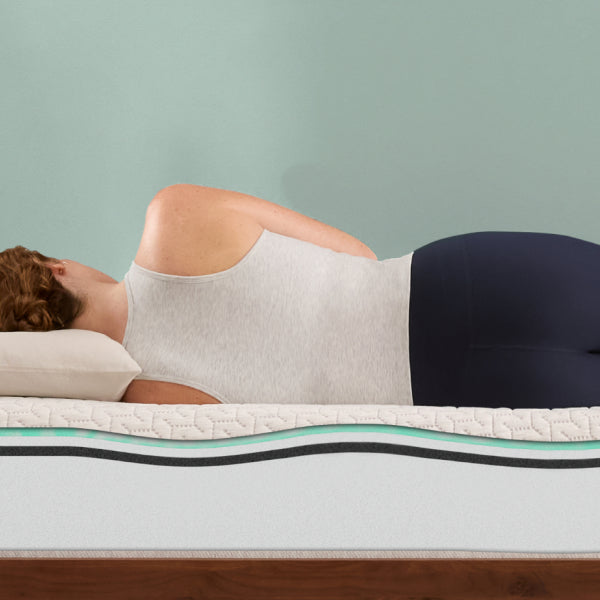 Person lying on a Tuft and Needle mattress with a visible mattress topper, against a plain background