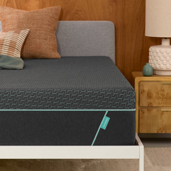 Tuft & Needle Gray mattress on a bed with pillows and a wooden nightstand in a bedroom setting