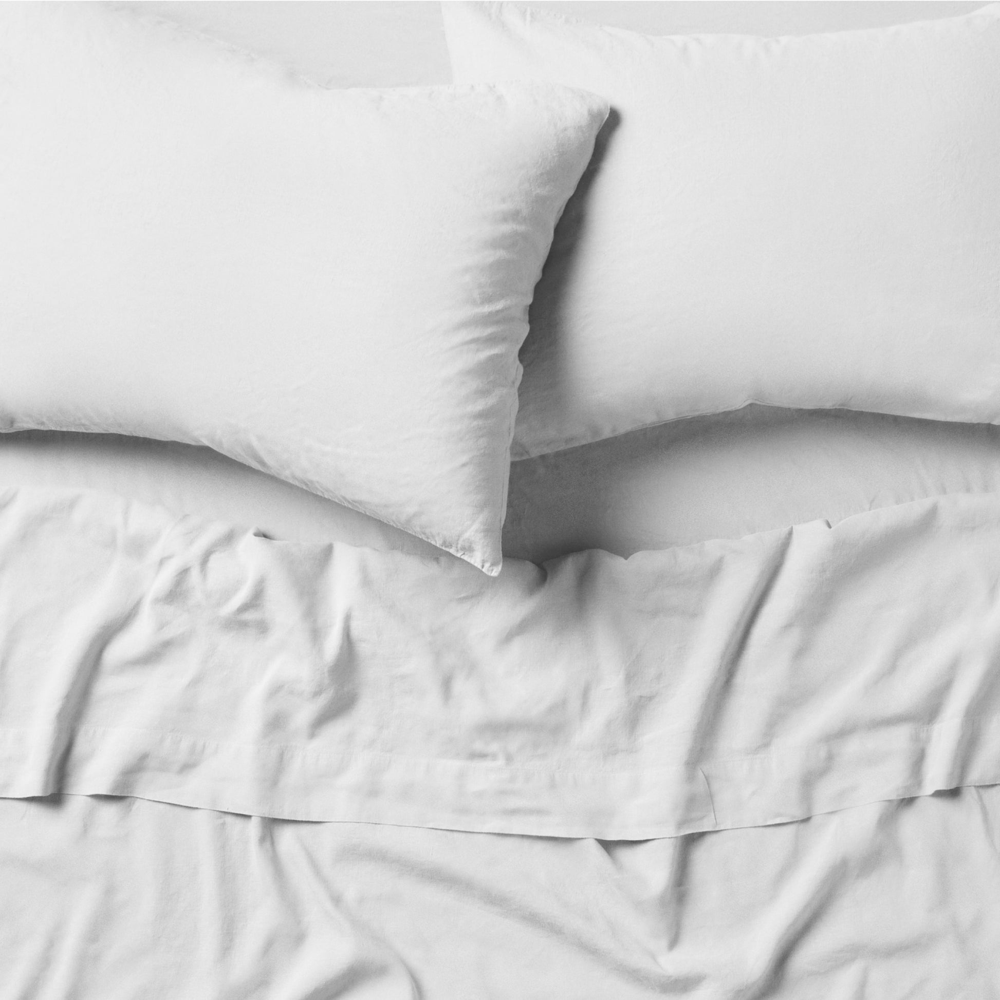 The Tuft and Needle Linen-Cotton Blend Sheet Set, 2 pillows on top of a sheet on a mattress || color: Cloud

