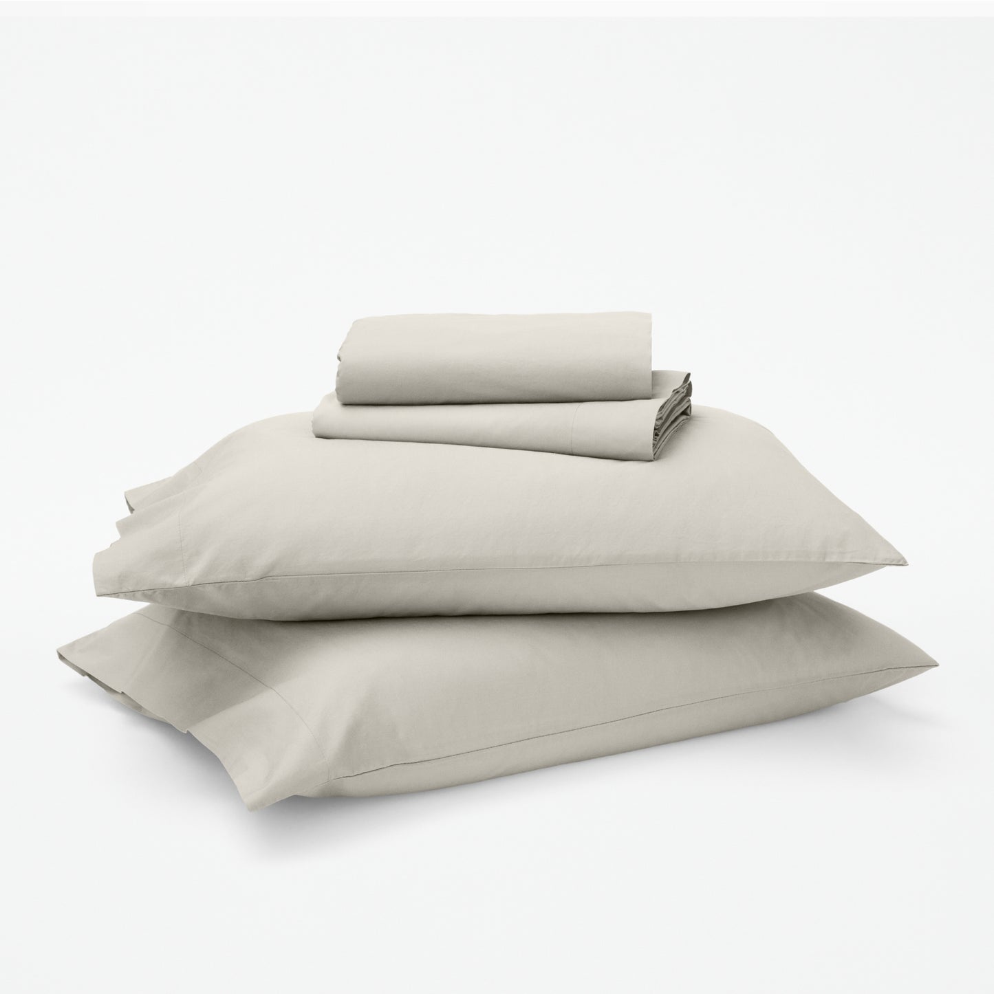 The Tuft and Needle Classic Percale Sheet Set, 1 sheet and pillowcases stacked on top of 2 pillows || color: Sand
