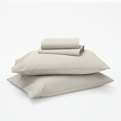 The Tuft and Needle Classic Percale Sheet Set, 1 sheet and pillowcases stacked on top of 2 pillows || color: Sand
