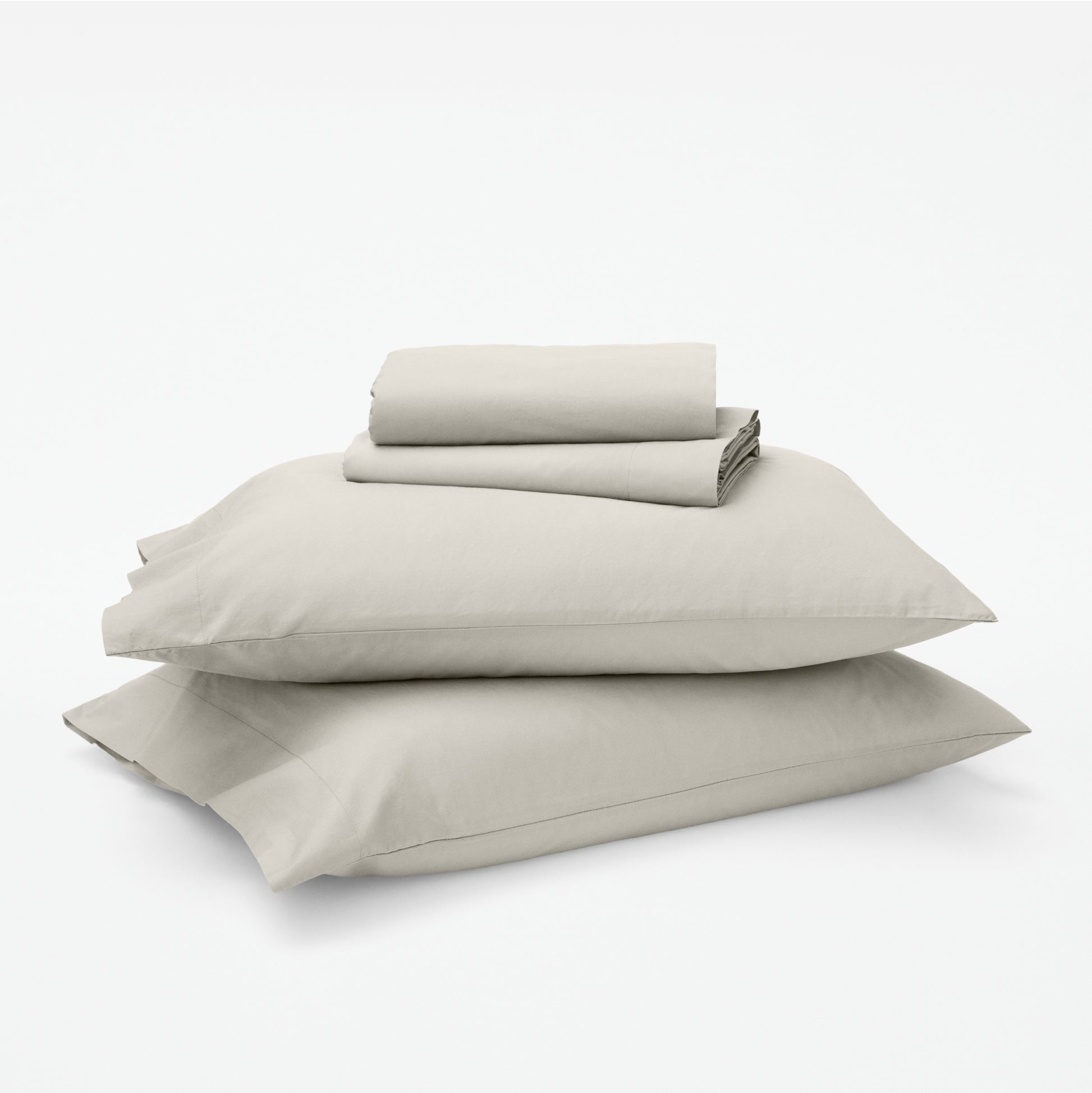 The Tuft and Needle Classic Percale Sheet Set, 1 sheet and pillowcases stacked on top of 2 pillows || color: Sand