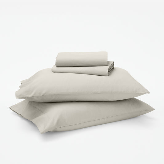 The Tuft and Needle Classic Percale Sheet Set, 1 sheet and pillowcases stacked on top of 2 pillows || color: Sand