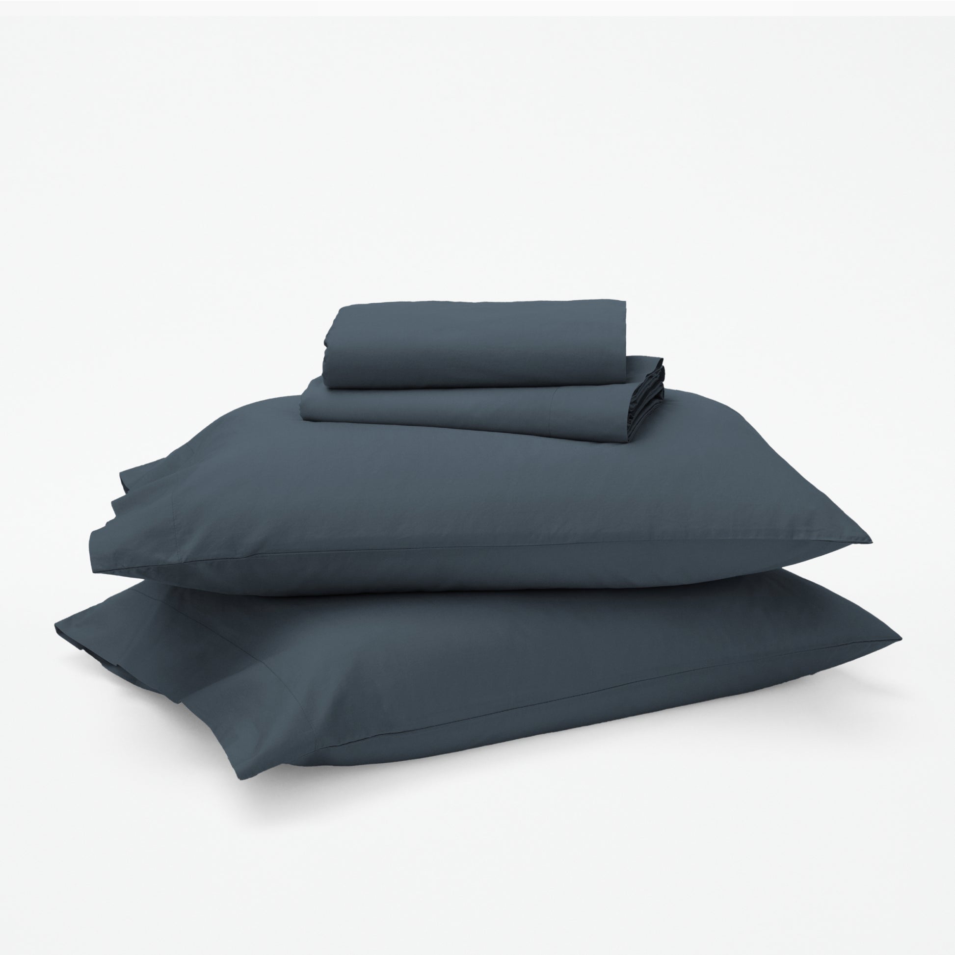 The Tuft and Needle Classic Percale Sheet Set, 1 sheet and pillowcases stacked on top of 2 pillows || color: Slate
