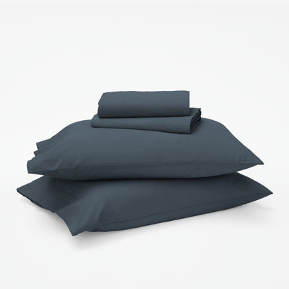 The Tuft and Needle Classic Percale Sheet Set, 1 sheet and pillowcases stacked on top of 2 pillows || color: Slate