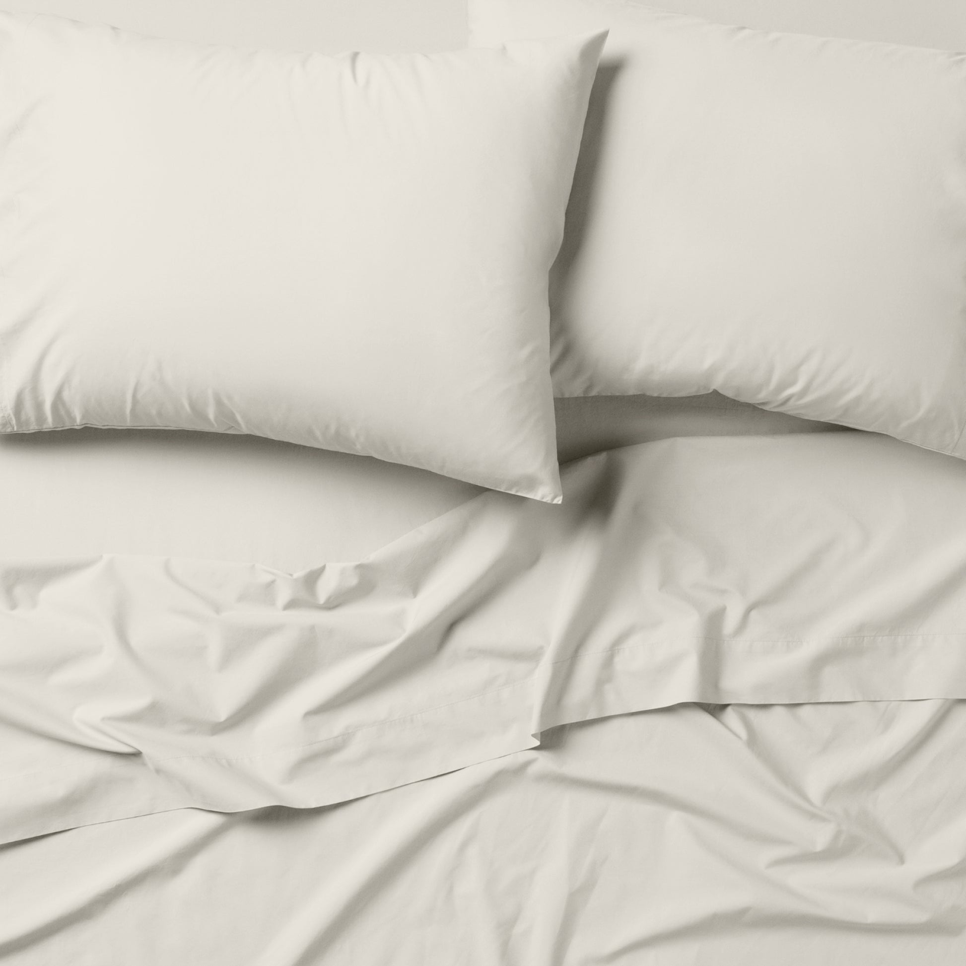 The Tuft and Needle Classic Percale Sheet Set, 2 pillows on top of a sheet on a mattress || color: Sage
