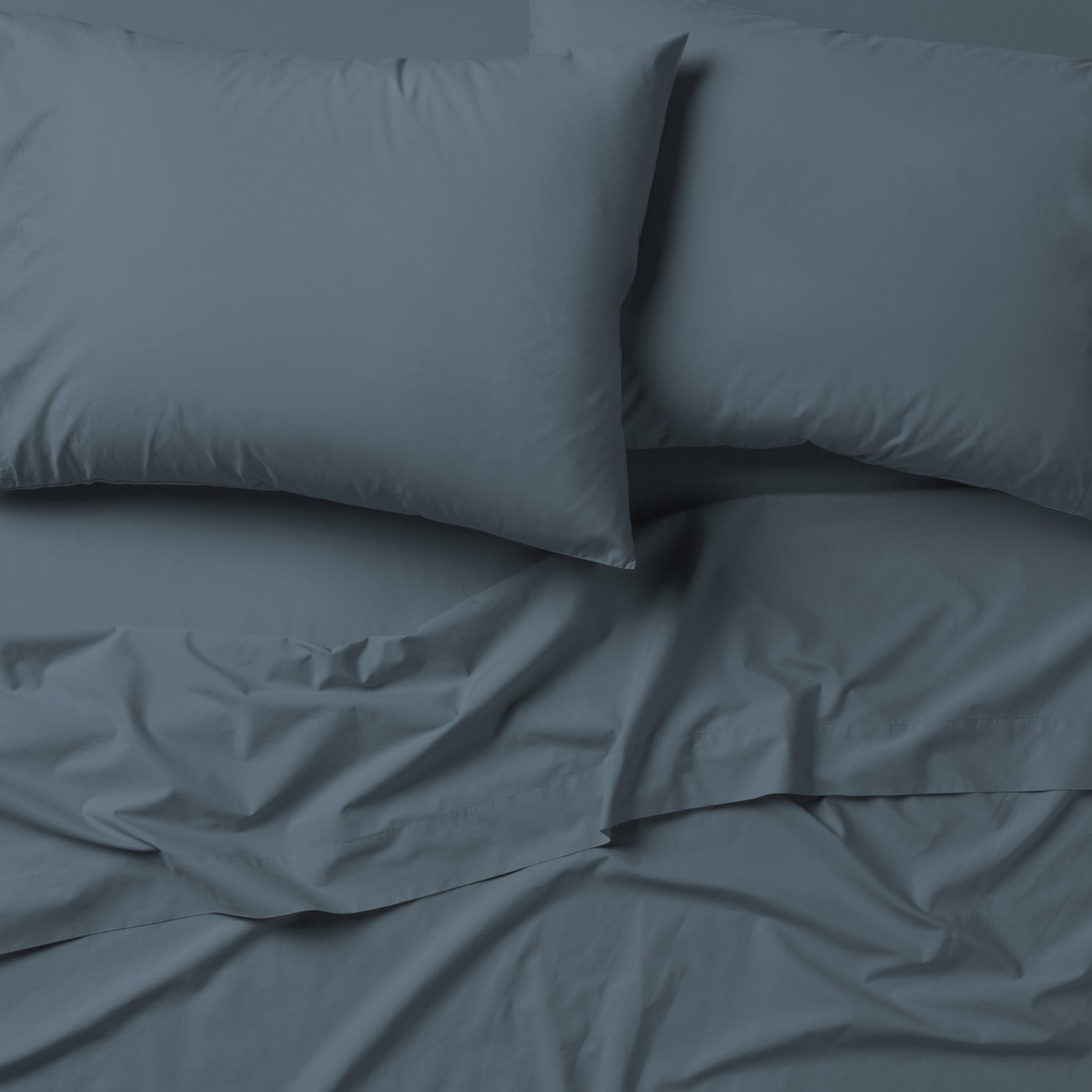 The Tuft and Needle Classic Percale Sheet Set, 2 pillows on top of a sheet on a mattress || color: Slate
