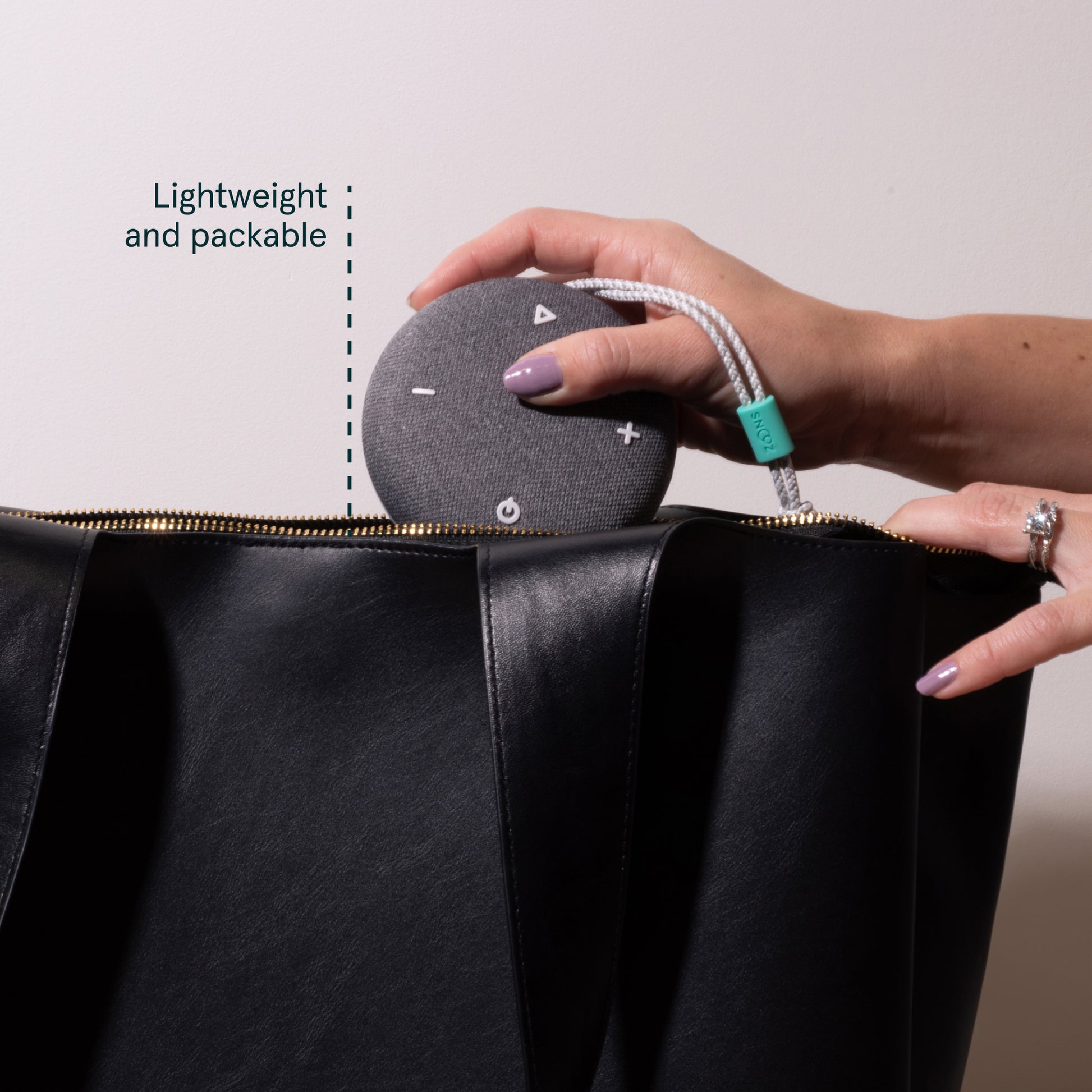 image showing a woman putting the Snooz Go Travel White Noise Machine in her bag.  