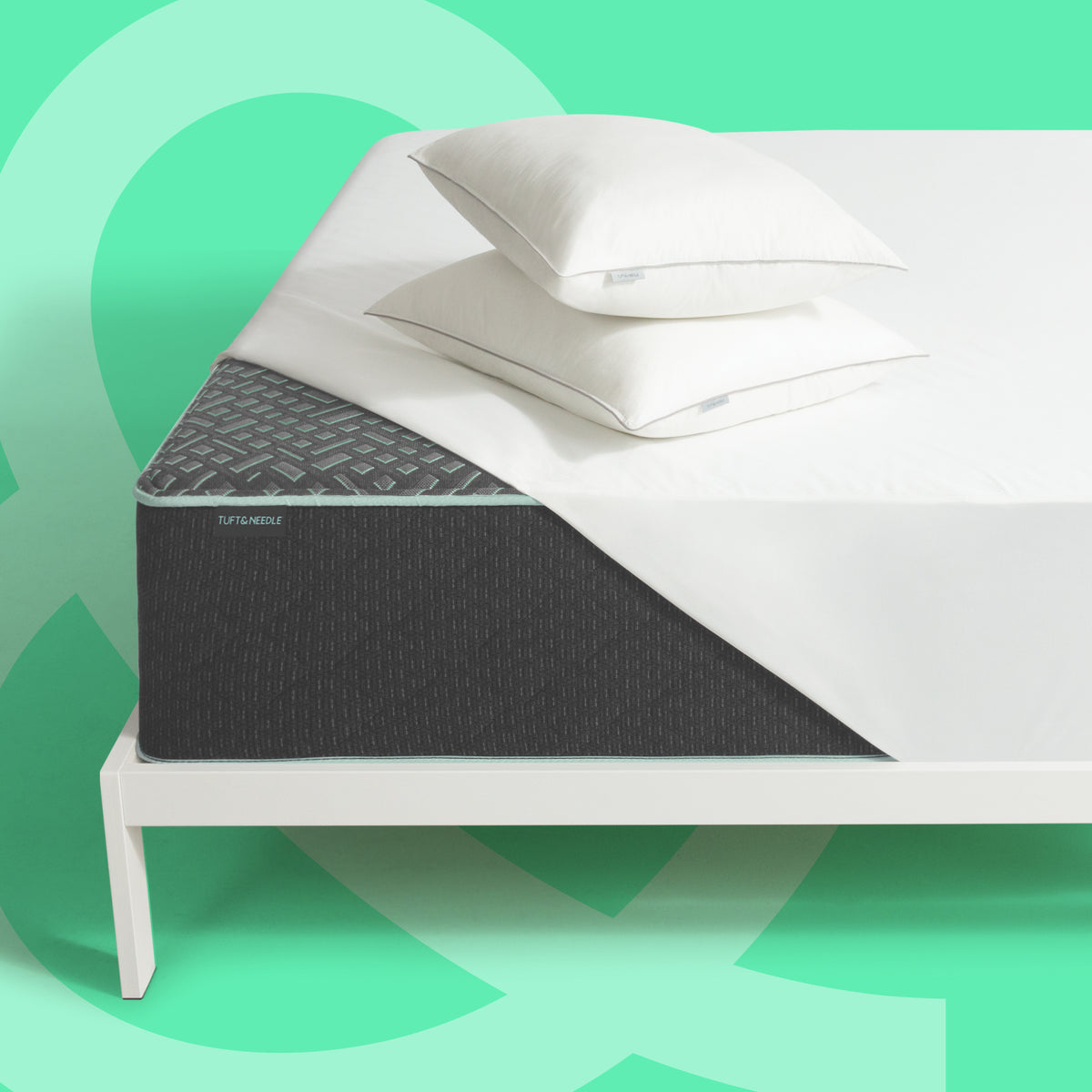 Tuft & Needle Mint Luxe Plush Hybrid Mattress with mattress protector and two pillows on a white bed frame