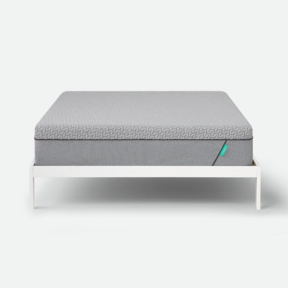 Tuft & Needle Gray mattress on a white bed frame against a white background
