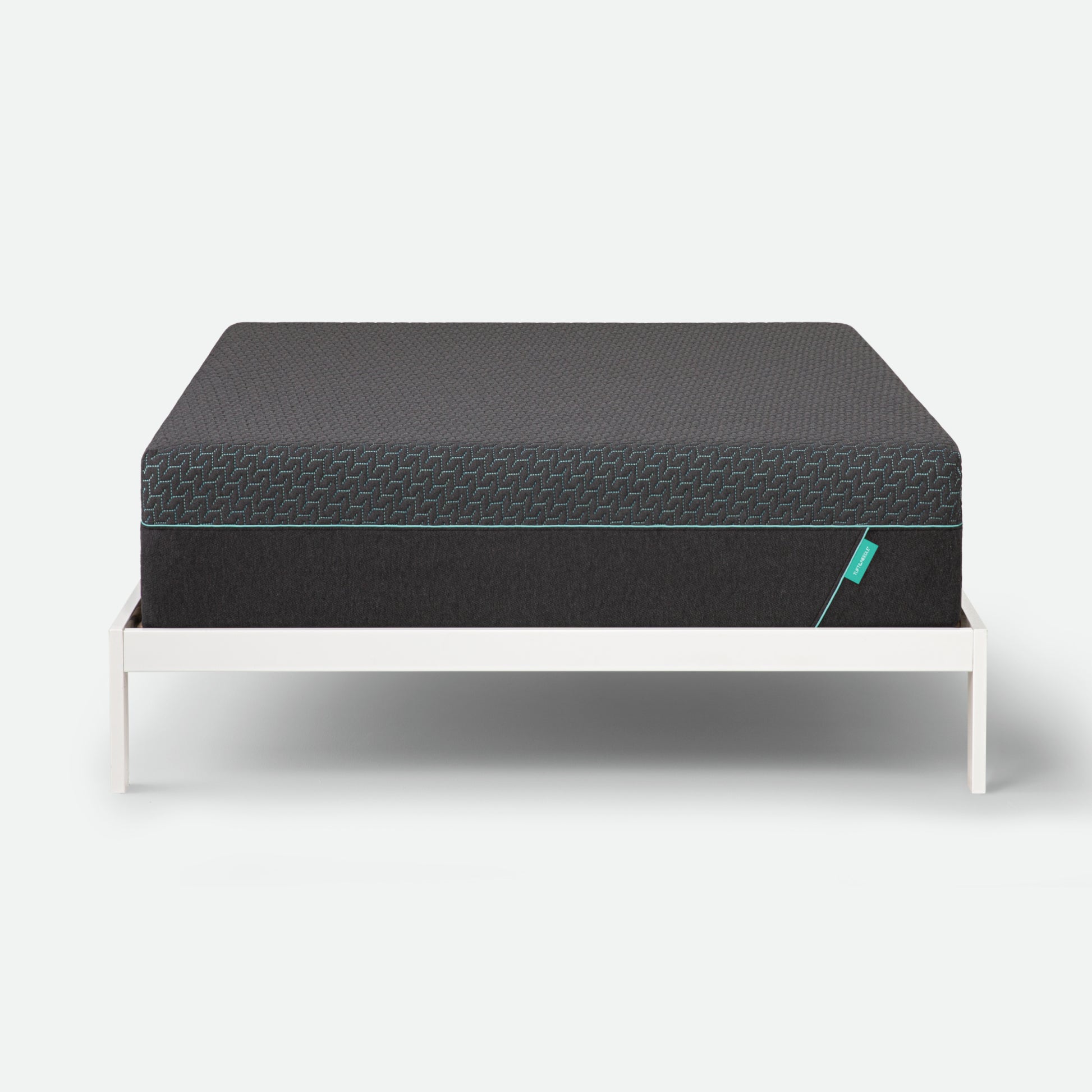 Tuft & Needle Black mattress on a white stand against a light gray background