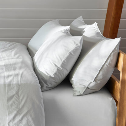 The Tuft and Needle Percale Pillowcase Set on a mattress in a bedroom||color:glacier