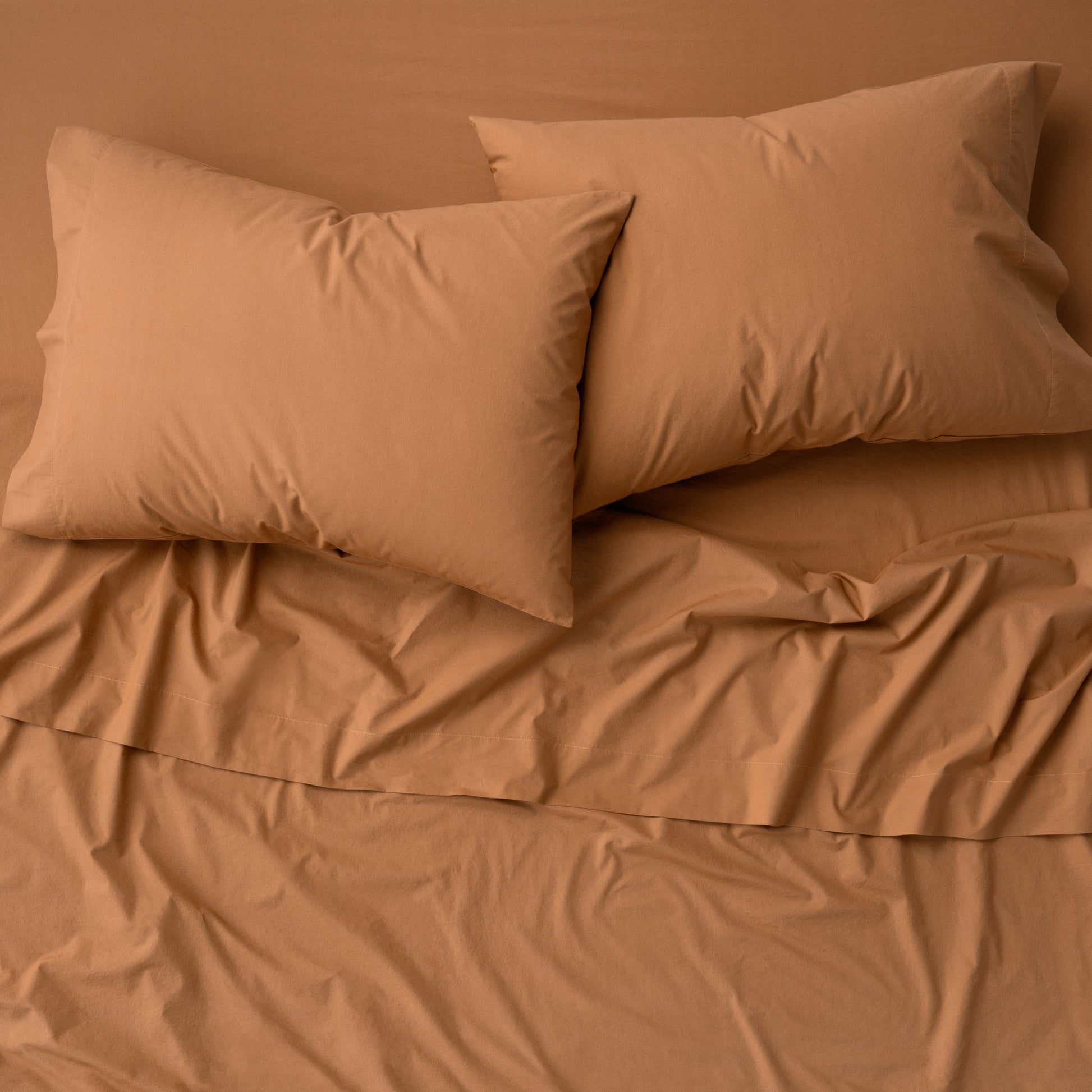 The Tuft and Needle Percale Pillowcase Set on a mattress||color:canyon
