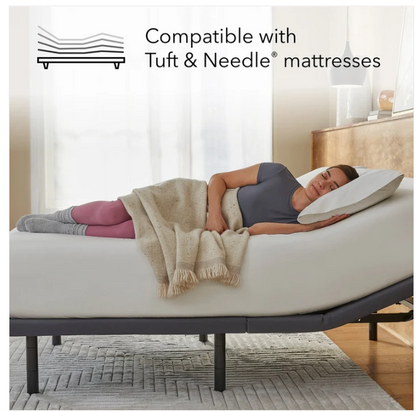 An adjustable bed with a person lying on it in a softly lit bedroom. The bed is shown with a mattress fitted, and text at the top reads 'Compatible with Tuft & Needle mattresses' with a small mattress icon.