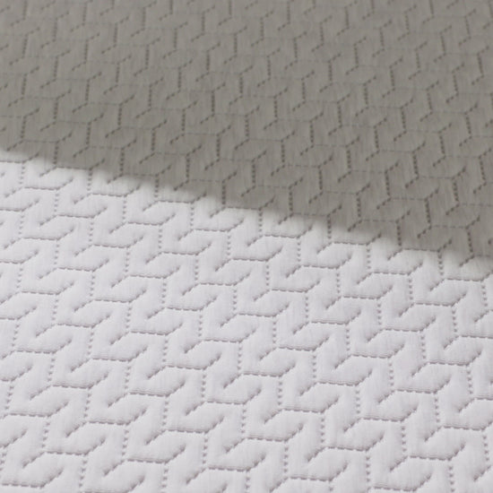 Woman presses hand on hybrid mattress.